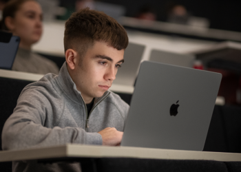 Student používá iPhone a Mac s funkcemi zpřístupnění