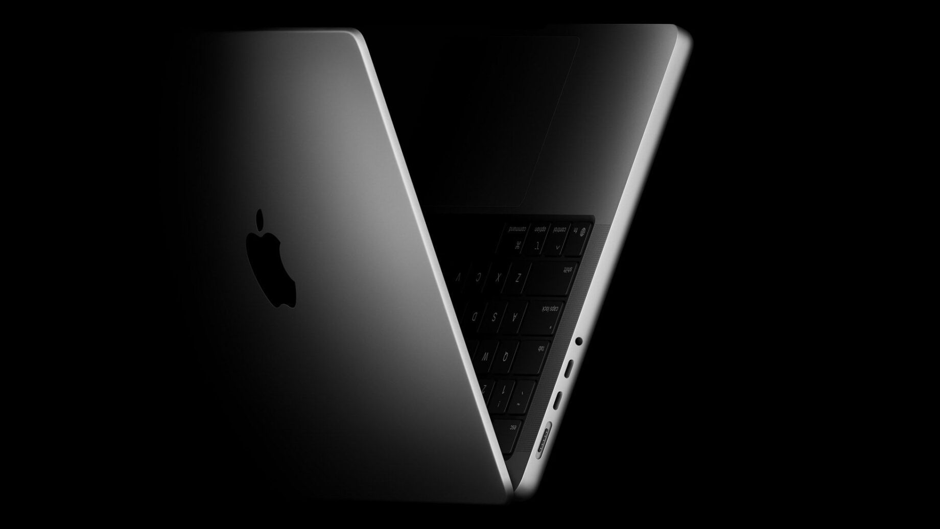 MacBook Pro na stole vedle OLED displeje