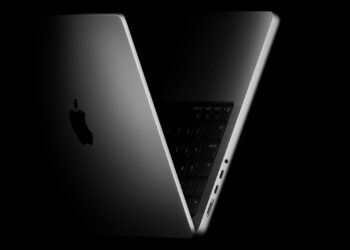 MacBook Pro na stole vedle OLED displeje